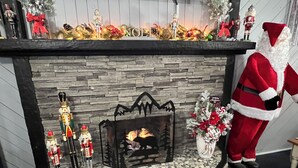 A fireplace with a stone surround, decorated with nutcracker figurines, a Christmas tree, and a Santa Claus figure. - Eastern Inn & Suites (North Conway)