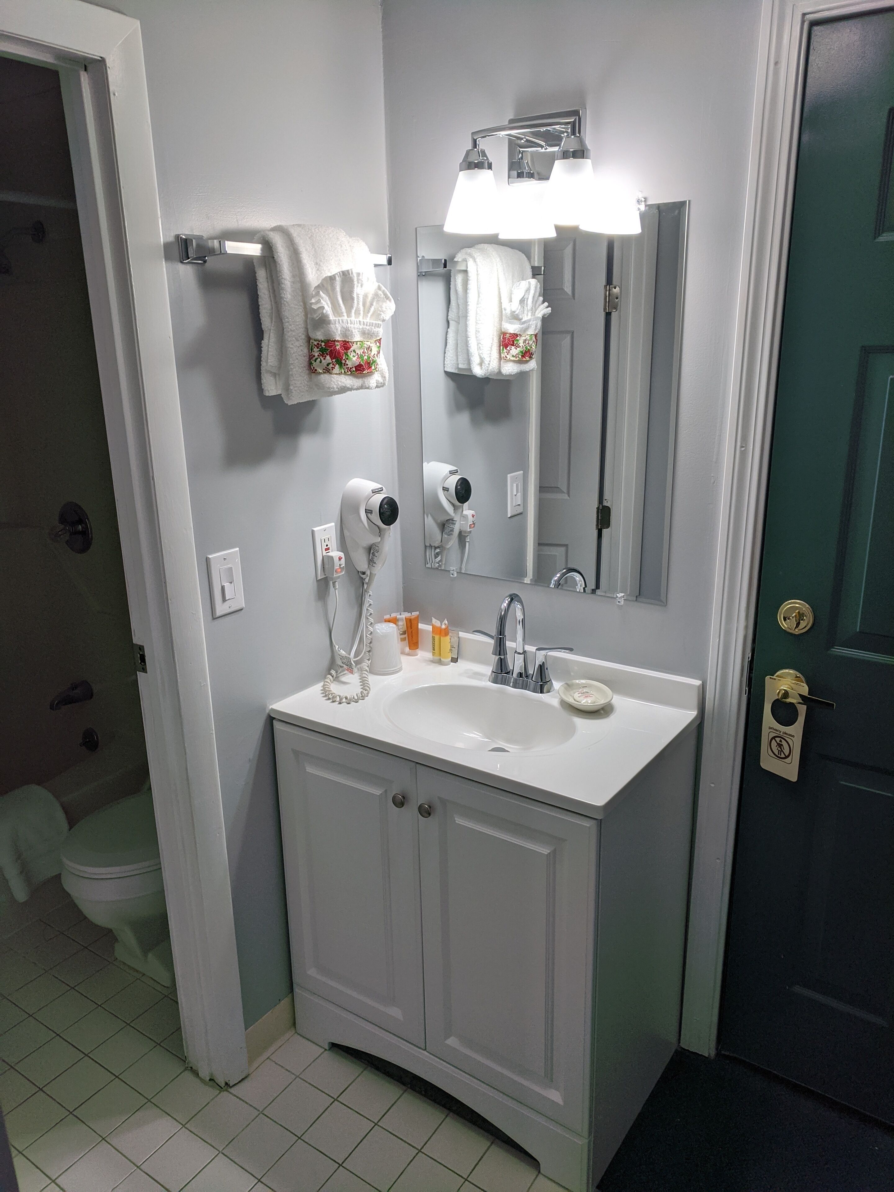A bathroom with a white sink, a mirror, a hairdryer, and a towel rack.