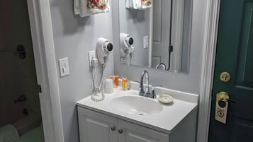 A bathroom with a white sink, a mirror, a hairdryer, and a towel rack.