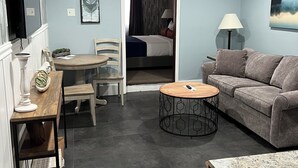 A modern living room with a sofa, coffee table, and dining area. - Eastern Inn & Suites (North Conway)