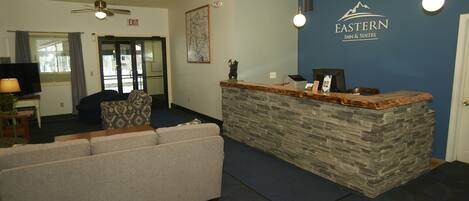 A reception area with a stone counter, a sofa, a ceiling fan, and a wall-mounted sign for Eastern Inn & Suites.