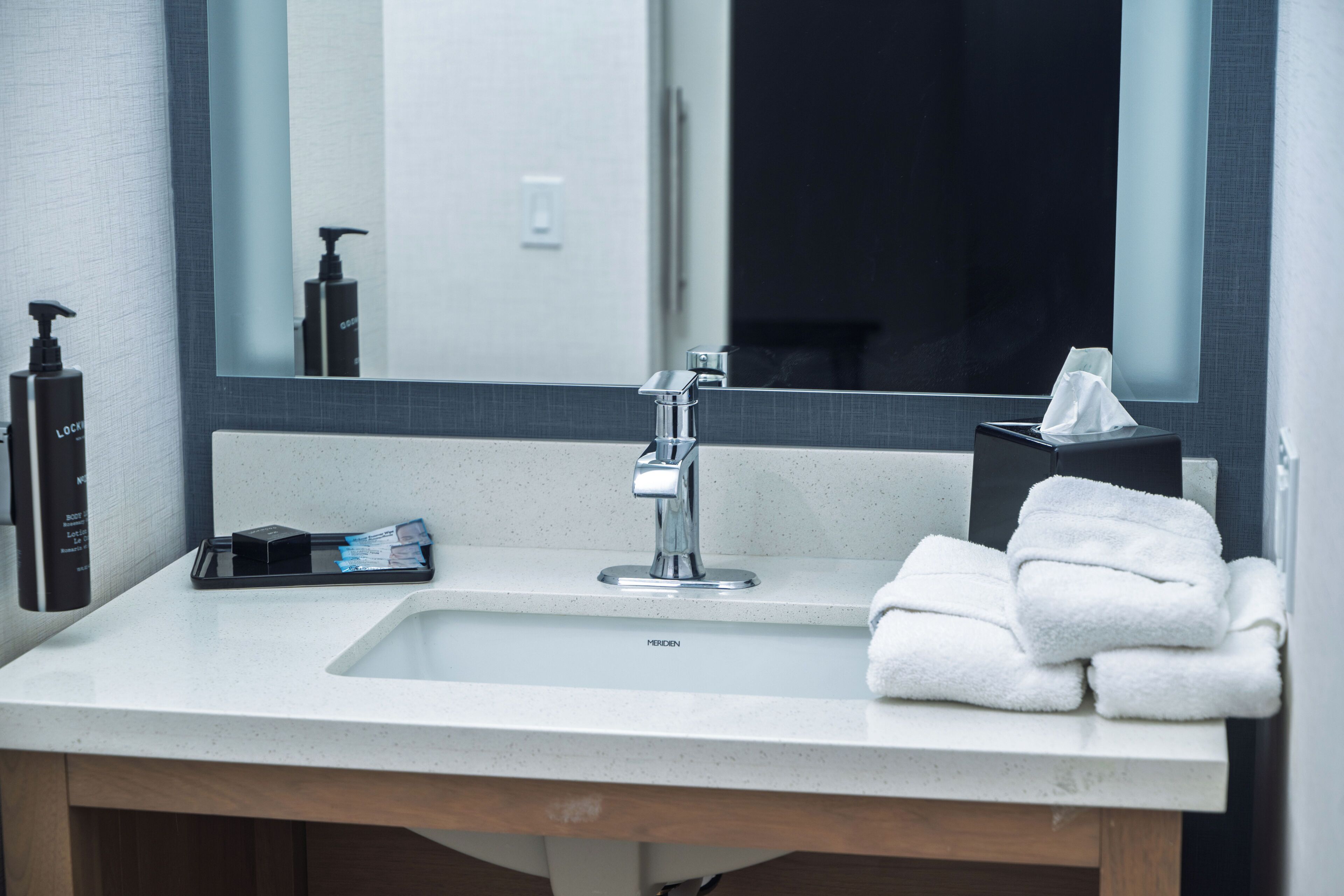 A bathroom with a sink, mirror, and toiletries.