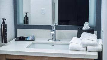 A bathroom with a sink, mirror, and toiletries.