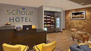 Een hotel receptie met een modern design, inclusief een receptiebalie, zithoek en een bakstenen muur met een ingelijst kunstwerk.