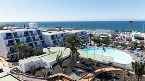 Een hotel met meerdere verdiepingen, een zwembad op het dak en uitzicht op zee.