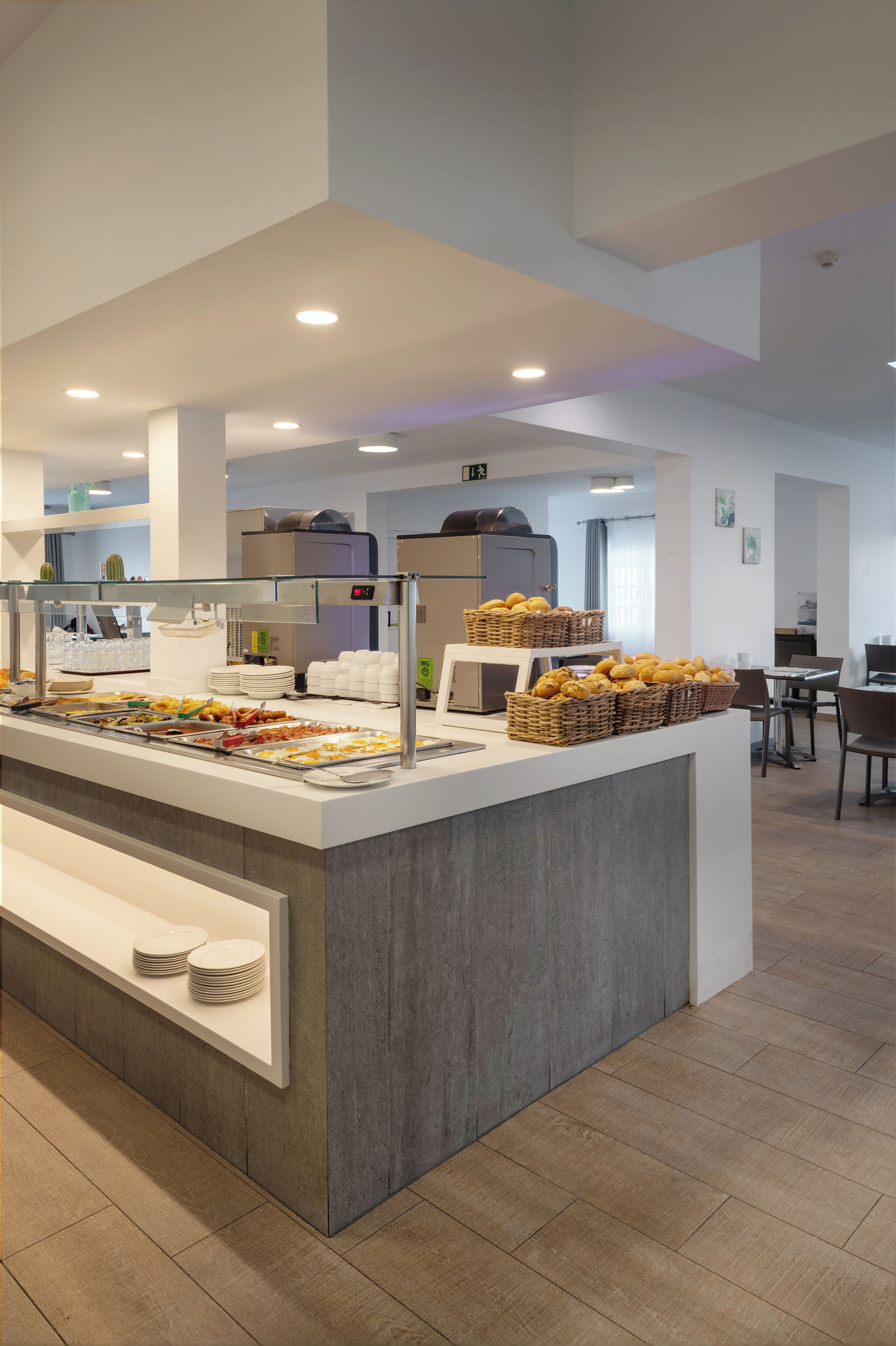 Zona de bufé con diferentes opciones de comida y un área de descanso al fondo.