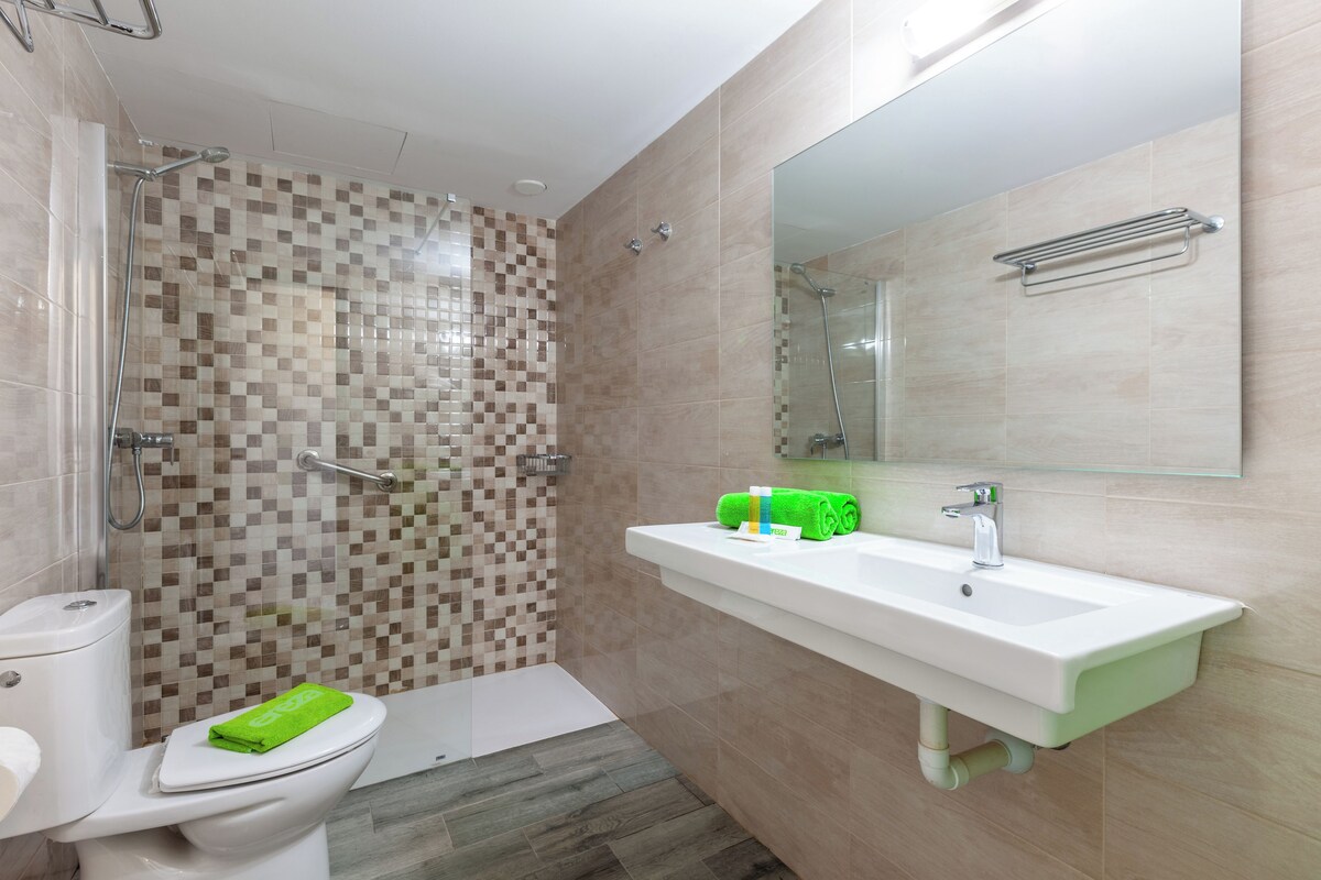Een moderne badkamer met douche, toilet en wastafel.