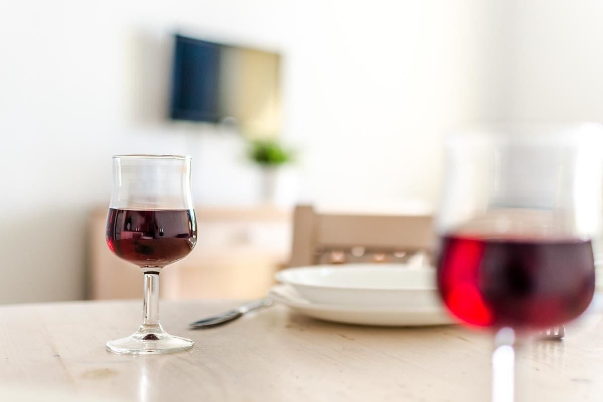 Een eettafel met een glas rode wijn en een bord.