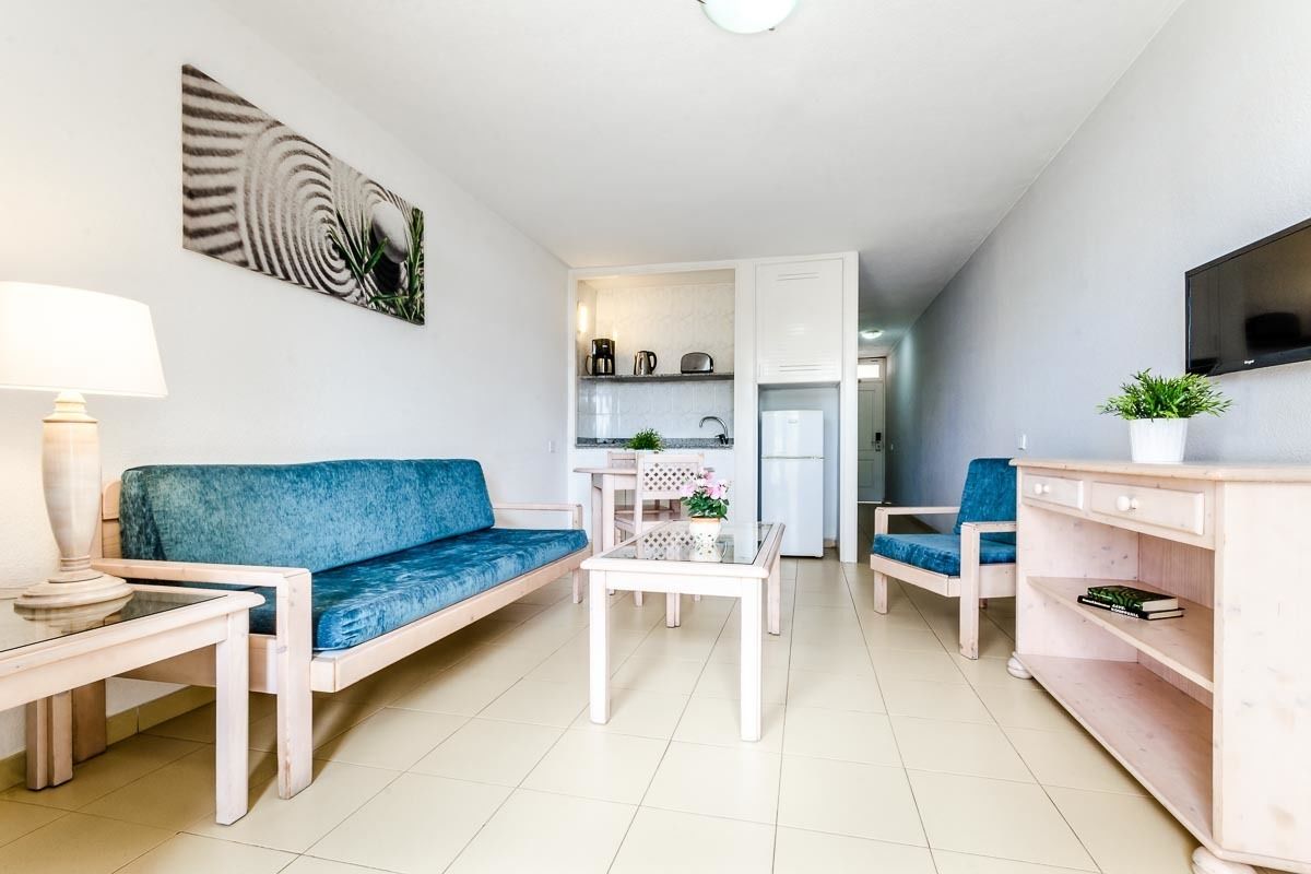 Una sala de estar moderna con un sofá, una mesa de centro y un televisor sobre un mueble.