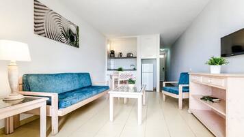 Una sala de estar moderna con un sofá, una mesa de centro y un televisor sobre un mueble.