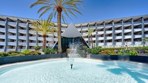 A hotel with a central fountain, palm trees, and a multi-story building with balconies.