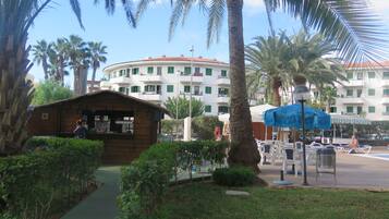 Un resort con una capanna di legno, palme e una zona piscina con lettini.