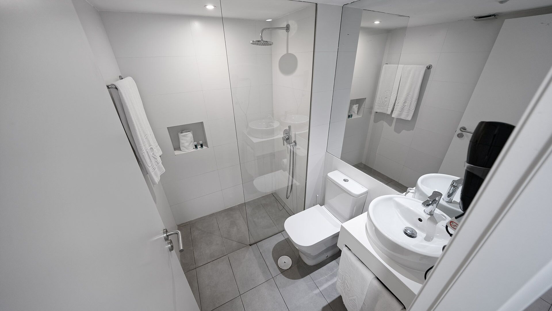 A modern bathroom with a glass-enclosed shower, a toilet, and a sink.
