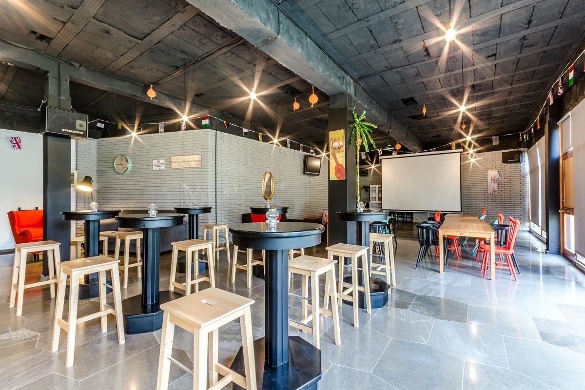 Un espace bar moderne avec des tabourets, des tables et un grand écran.