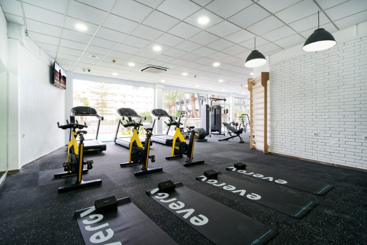 Un gimnasio con cintas de correr, bicicletas estáticas y máquinas de pesas.