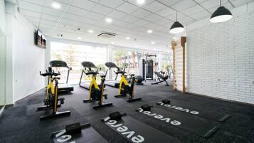 Un gimnasio con cintas de correr, bicicletas estáticas y máquinas de pesas.