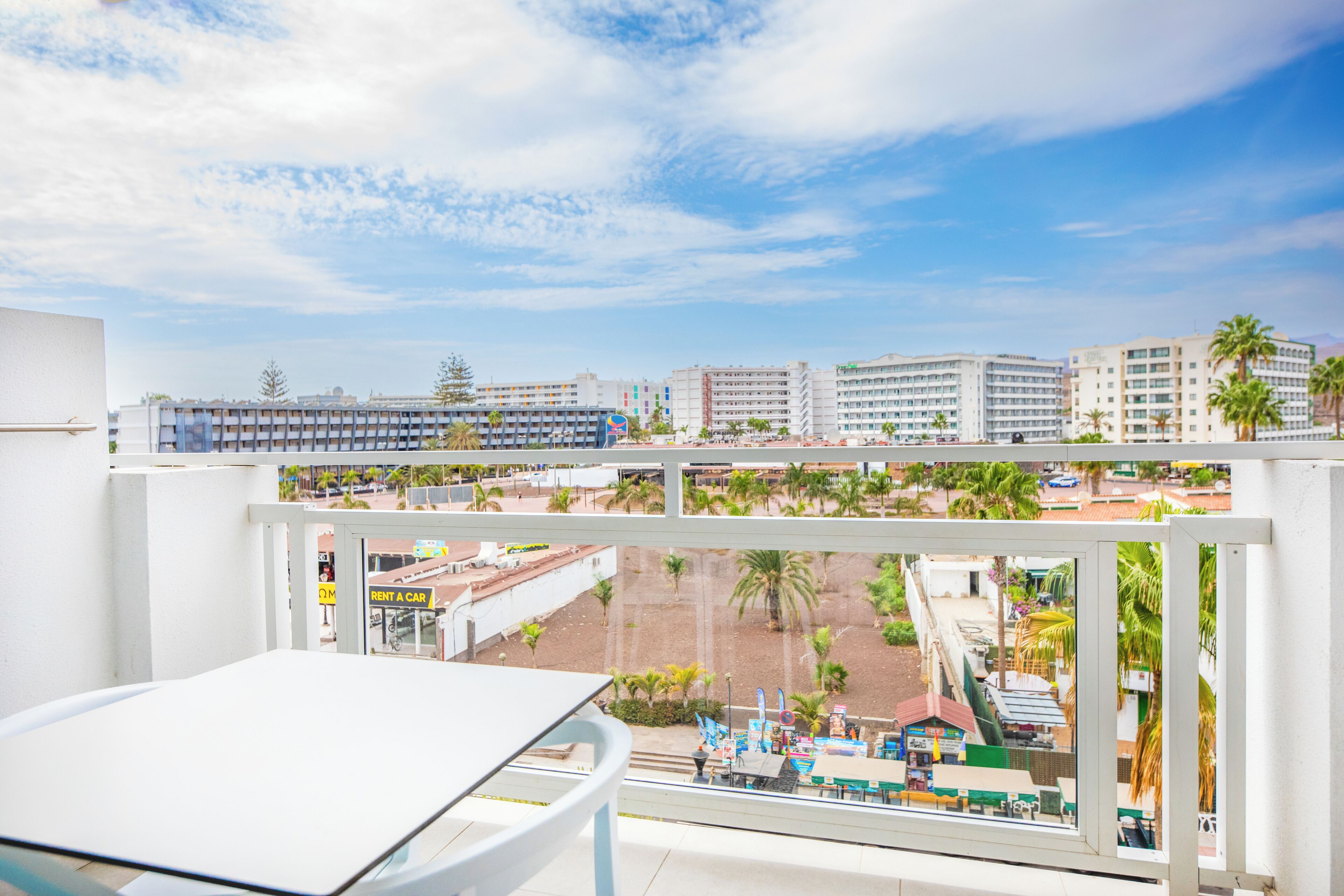 A balcony with a view of a cityscape, including buildings and palm trees.