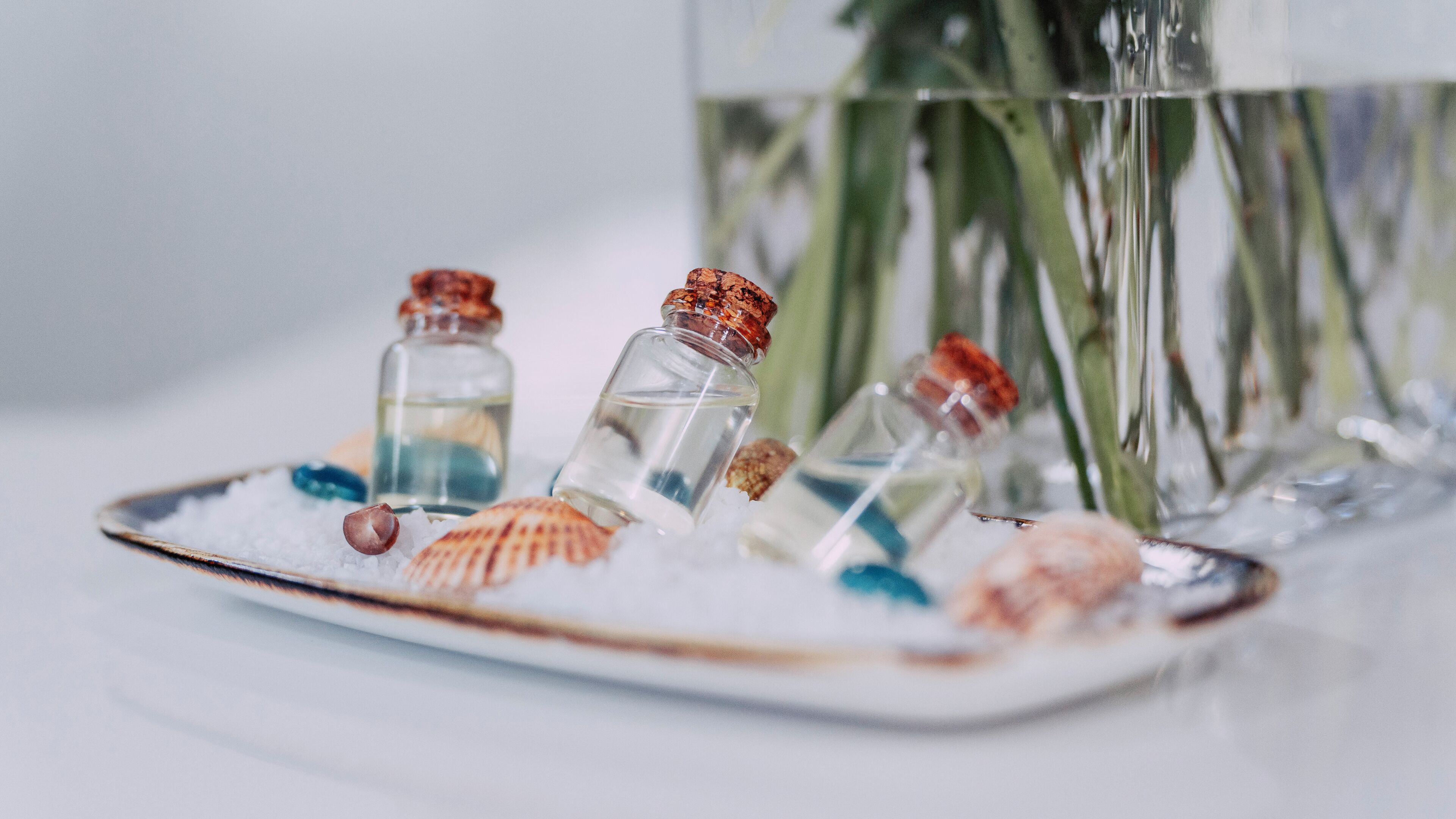 A decorative arrangement with seashells and small glass bottles on a plate.