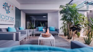 A modern lounge area with grey sofas and blue cushions, a white coffee table with candles, and a large plant on the right. - Labranda Hotel Marieta & Spa - Adults only (San Bartolomé de Tirajana)