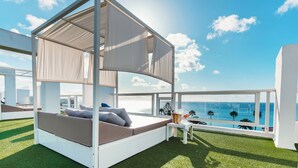 A modern outdoor bedroom with a canopy bed, a small table with drinks, and a view of the ocean. - Labranda Hotel Marieta & Spa - Adults only (San Bartolomé de Tirajana)