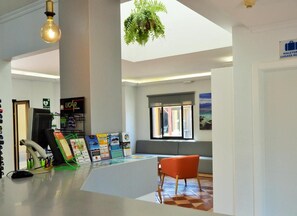 Zona de recepción con escritorio, computadora y área de asientos.