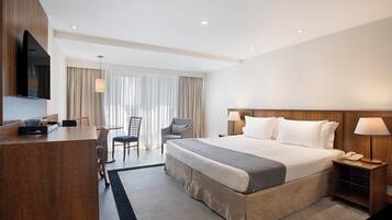 Une chambre d’hôtel avec un grand lit, un bureau, une chaise, une télévision et une lampe.