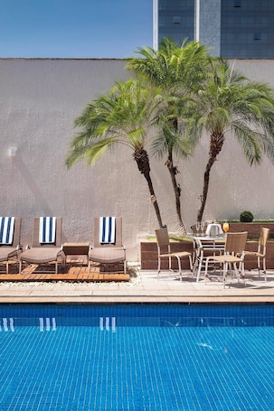 Una piscina al aire libre, sillones reclinables de piscina