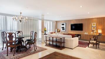 A modern living room with a dining area, a sofa, a TV, and a chandelier.