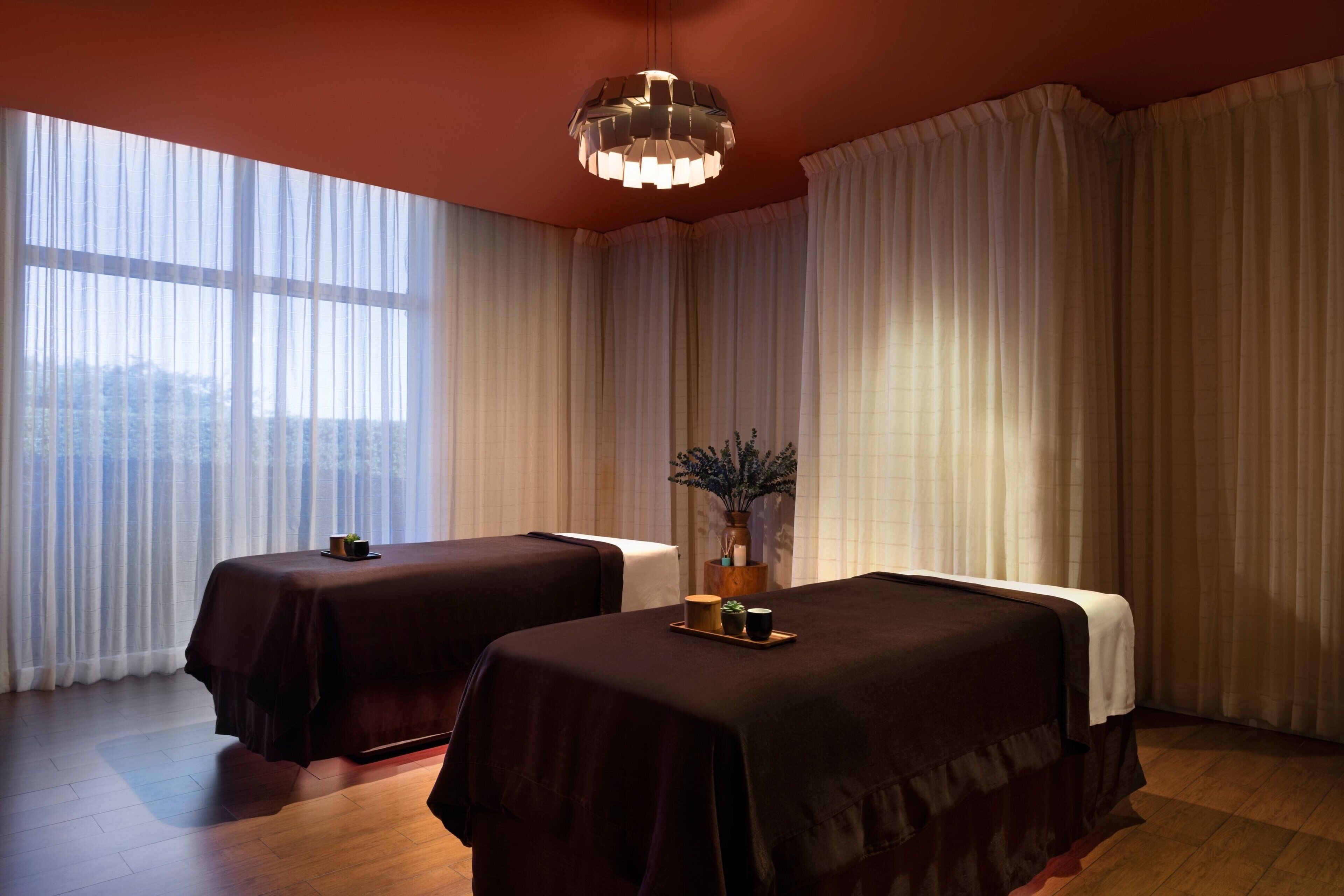 Un cuarto de spa con dos camas, un ventanal grande y una lámpara colgante.