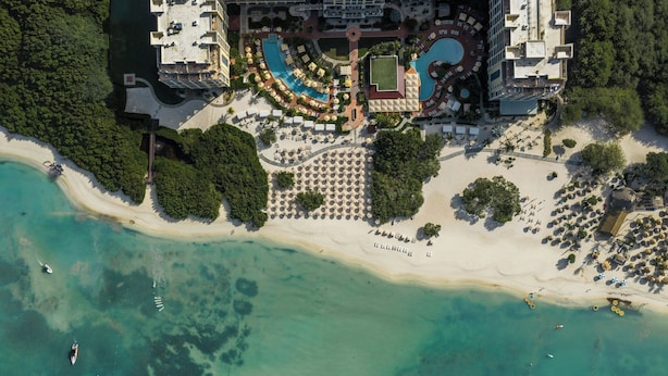 An aerial view of a resort with a large pool, beach, and multiple buildings. - The Ritz-Carlton, Aruba (Noord)