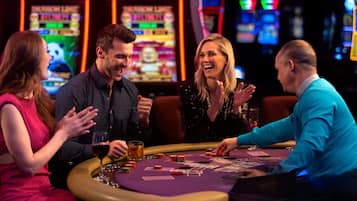 Ein Casino mit einem Blackjack-Tisch, mehreren Spielautomaten und einer Bar.