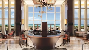 A spacious lobby with a central bar, large windows offering ocean views, and a modern chandelier. - The Ritz-Carlton, Aruba (Noord)