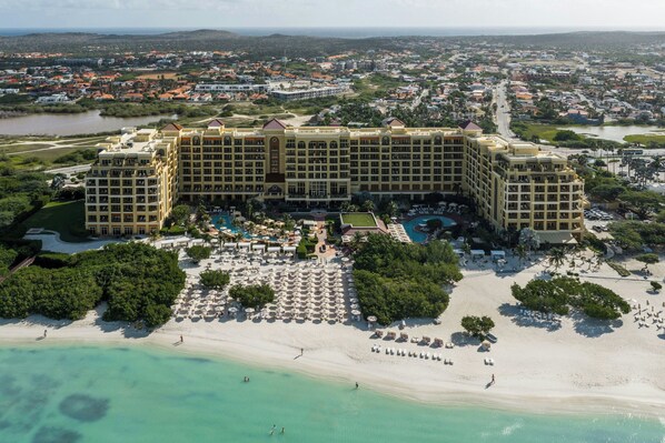 A large hotel with multiple buildings, a beach, and a pool area.