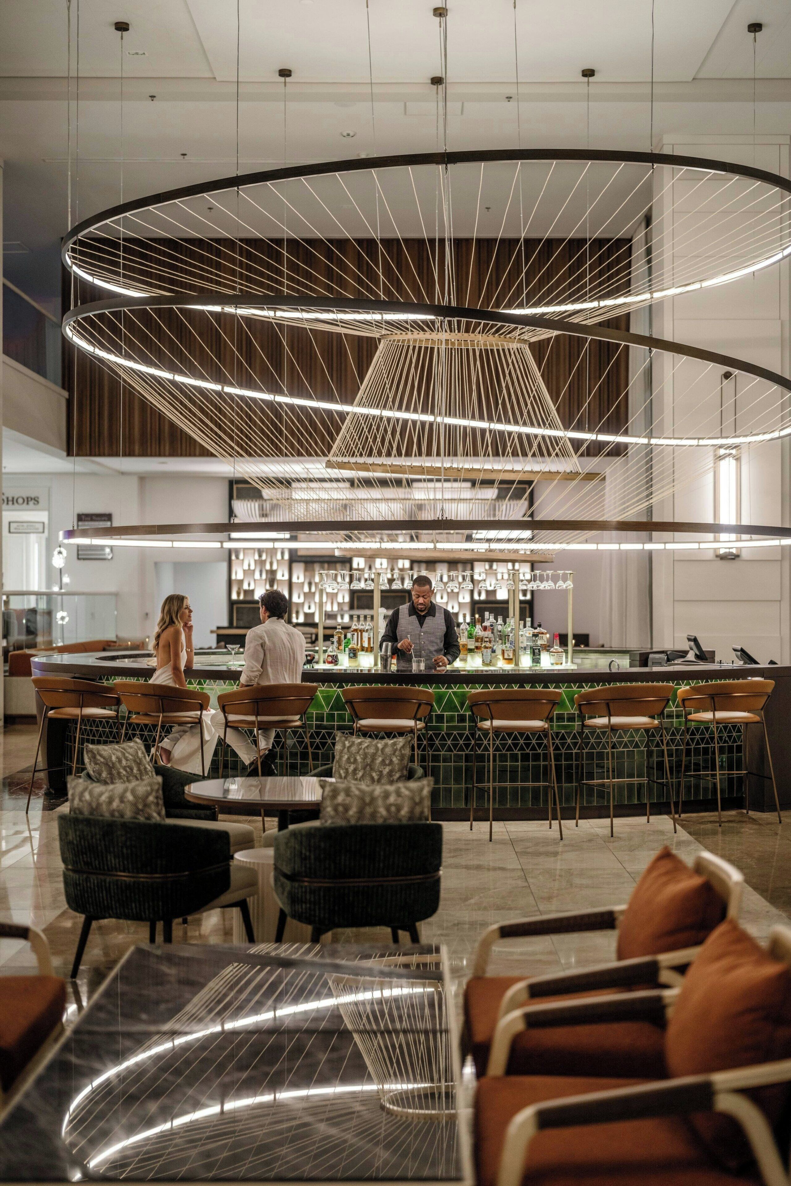 Un área de bar moderna con un diseño de techo circular, asientos con cojines y una barra.