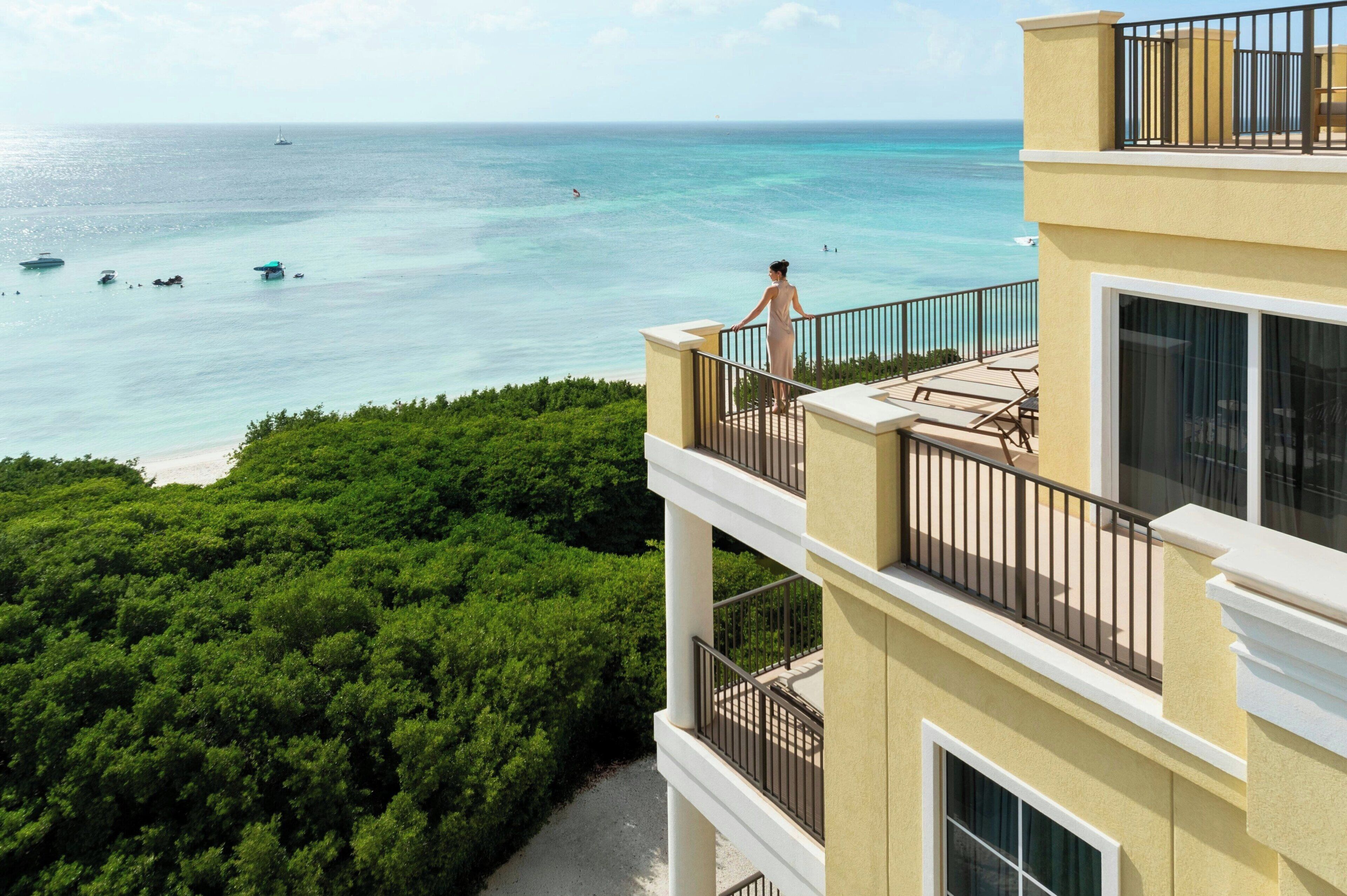 Ein mehrstöckiges Gebäude mit Balkonen mit Blick auf Strand und Meer.