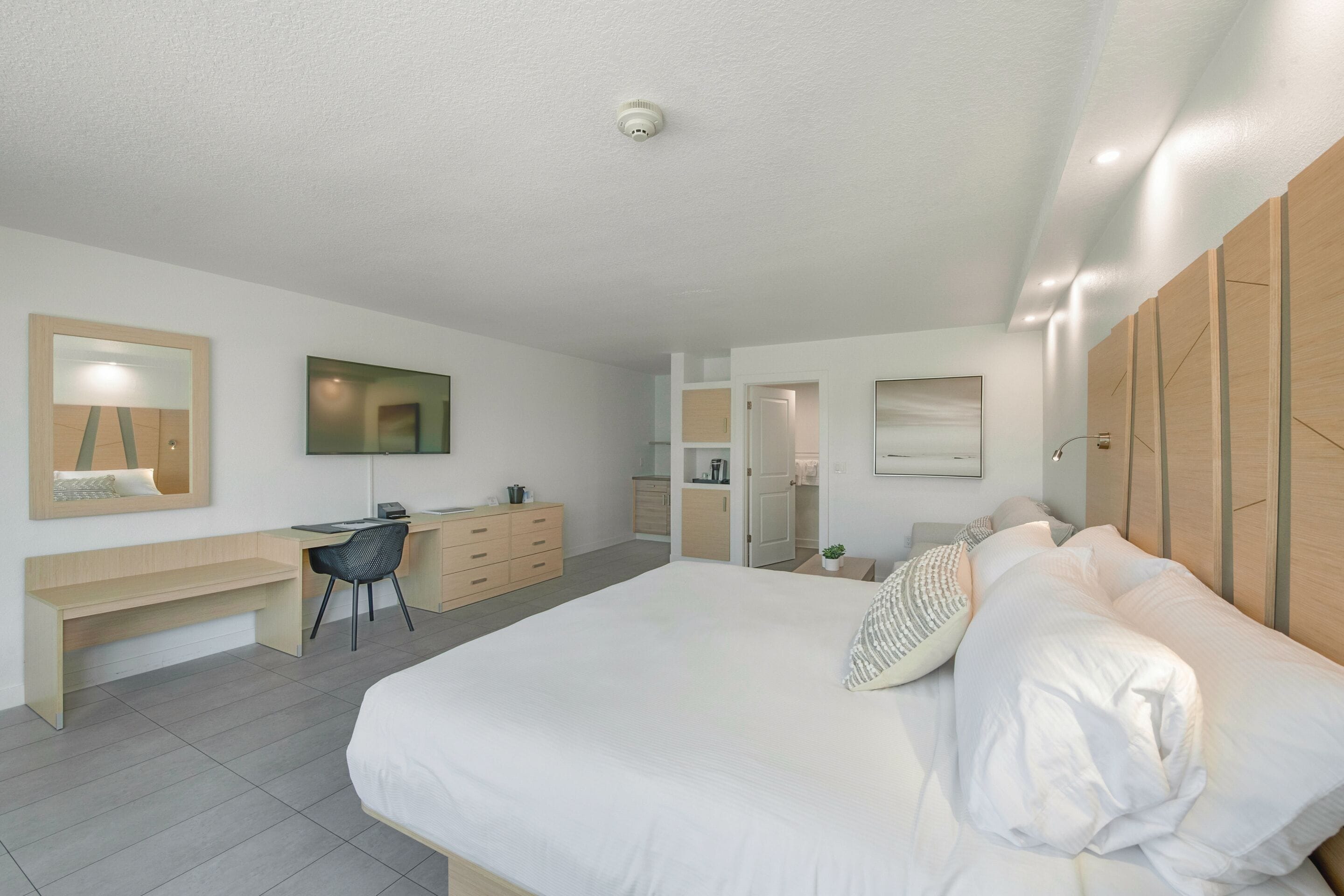 Un dormitorio moderno con una cama grande, un escritorio, una silla y un armario.