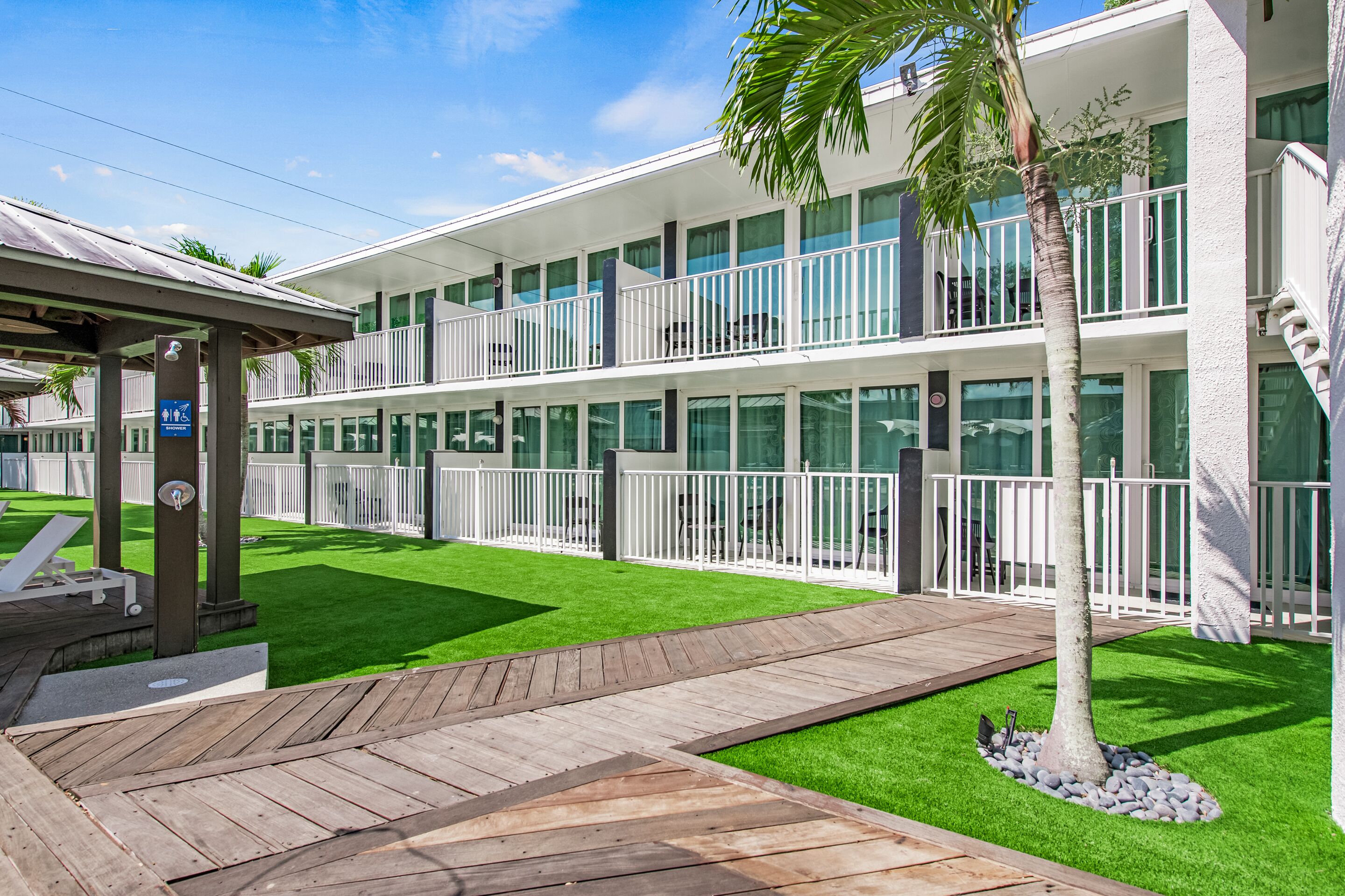 Un hotel moderno con estructura de dos pisos, terraza de madera al aire libre y un césped bien cuidado.