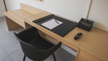A modern office desk with a notebook, pen, remote control, and a black tray.