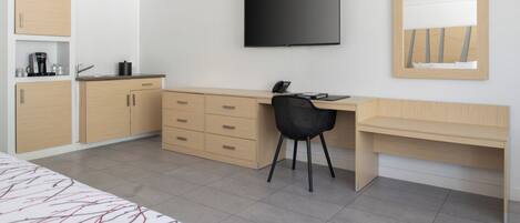 Une chambre d’hôtel moderne équipée d’un lit, d’un bureau, d’une chaise, d’une télévision et d’armoires intégrées.