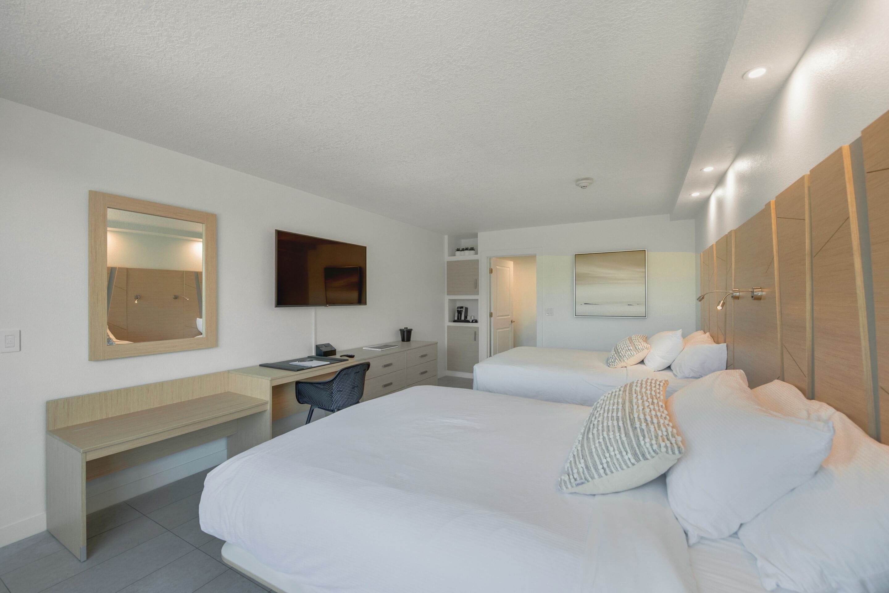 Una habitación de hotel moderna con dos camas, un escritorio, una silla y un armario.