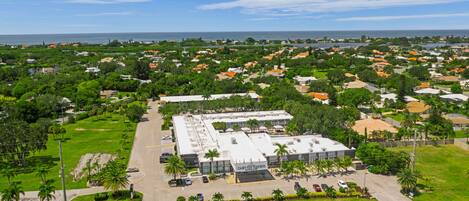 An aerial view of Casey Key Resorts Mainland, featuring a large building with a flat roof, surrounded by lush greenery and a parking lot.