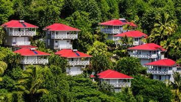 Un conjunto de edificios con tejados rojos y balcones blancos, rodeado de frondosa vegetación verde.