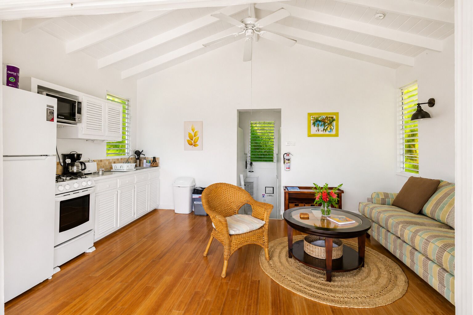 A compact living space with a kitchenette, a dining area with a round table, and a sofa.