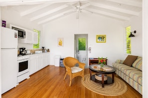 A compact living space with a kitchenette, a dining area with a round table, and a sofa.