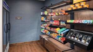 Eine Selbstbedienungsstation für Snacks und Getränke mit verschiedenen Speisen, Getränken und einem Kühlschrank.