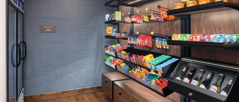 Eine Selbstbedienungsstation für Snacks und Getränke mit verschiedenen Speisen, Getränken und einem Kühlschrank.