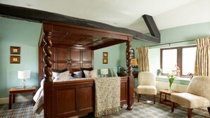 A traditional bedroom with a four-poster bed, two armchairs, a small table, and a window with curtains. - Burford House (Burford)