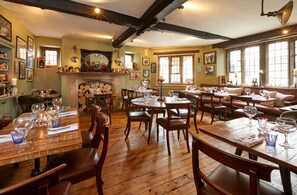 Ein gemütliches Restaurant mit Holzdielen und Essplatzanordnungen, mit Kamin und großen Fenstern.