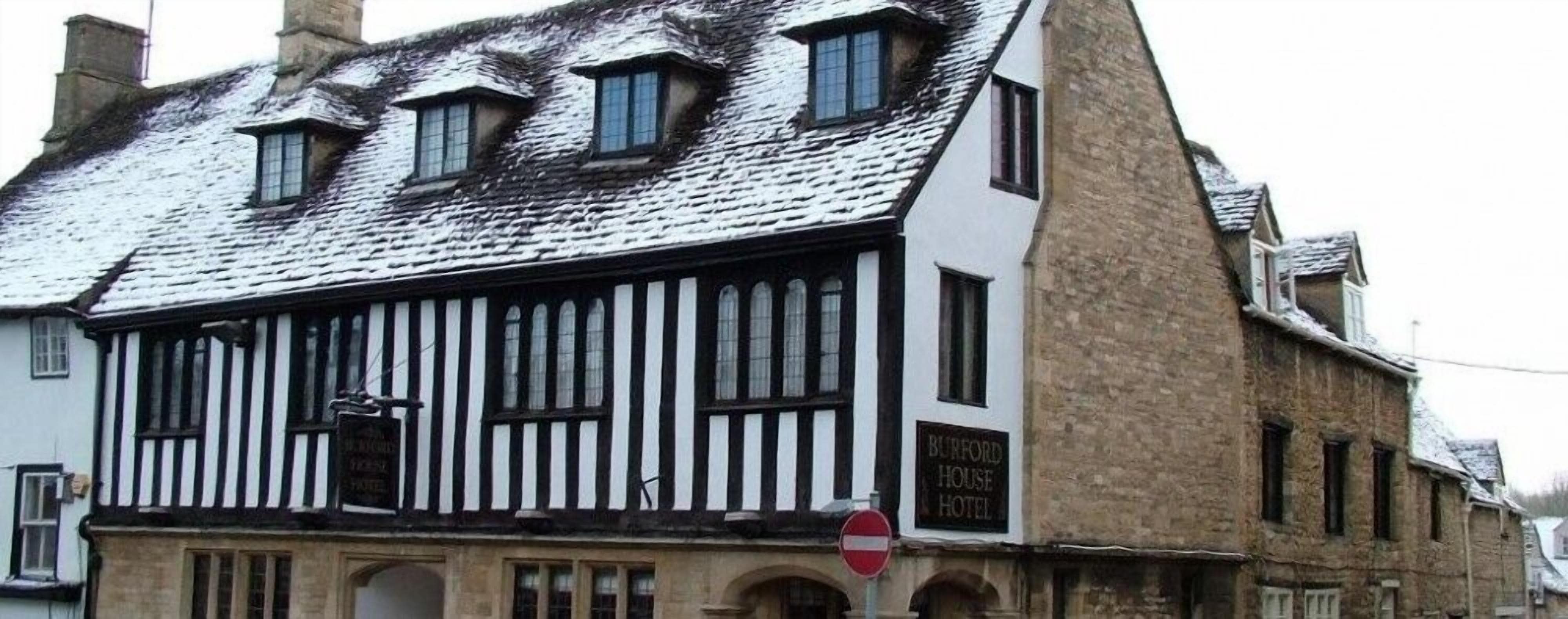 Un bâtiment traditionnel aux rayures noires et blanches, sur lequel on peut lire une enseigne indiquant qu’il s’agit de l’hôtel Burford House.