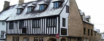 Un edificio tradicional con franjas negras y blancas y un cartel que indica que es el Burford House Hotel.